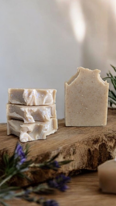 Peace, Clarity and Oats Soap Handmade soap bars near greenery on a wooden surface.